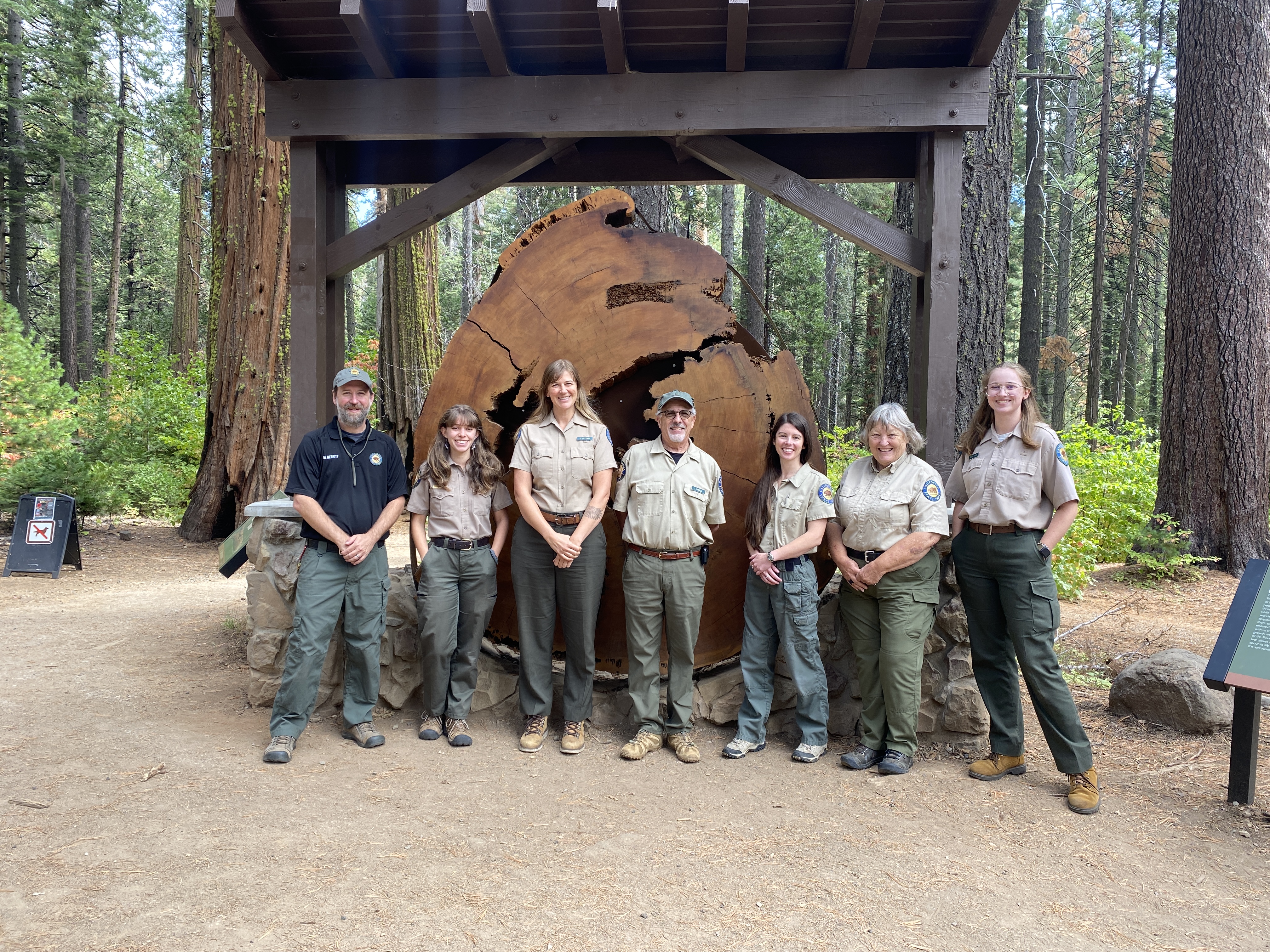 Seven Interpretive staff standing in front of the Pioneer Cabin Display 